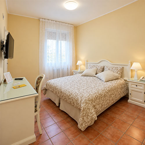 Camera matrimoniale dell’Hotel Villa Romana di Piazza Armerina con scrivania, TV e comodini